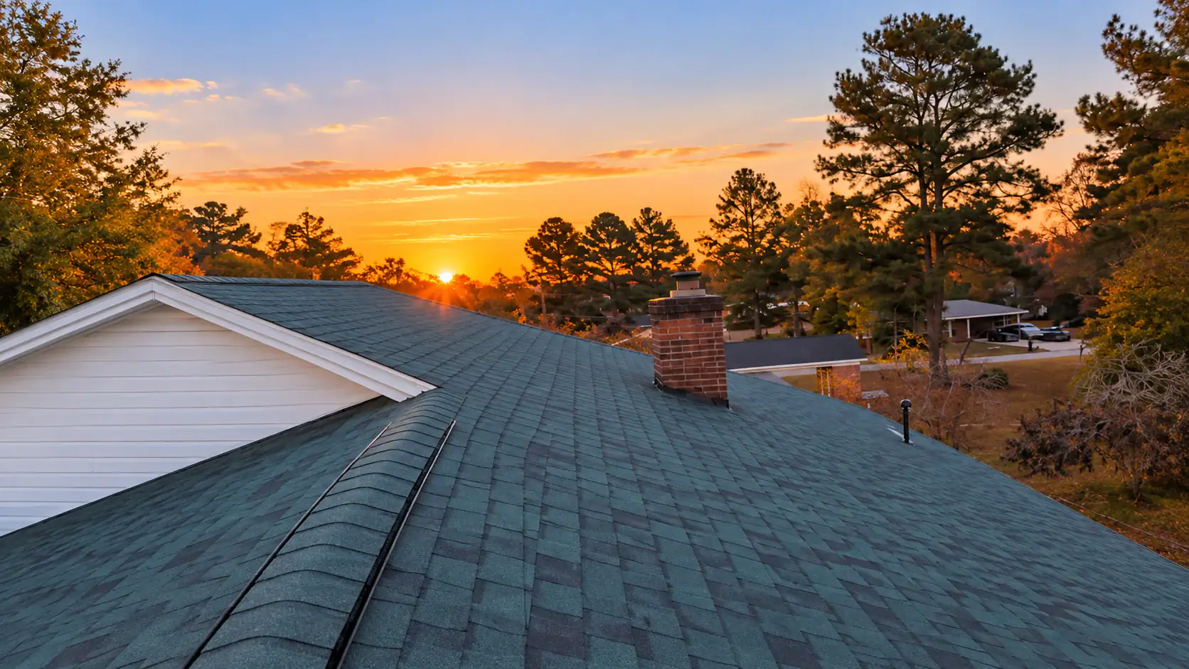 New dark shingle roof and brick chimney at sunset